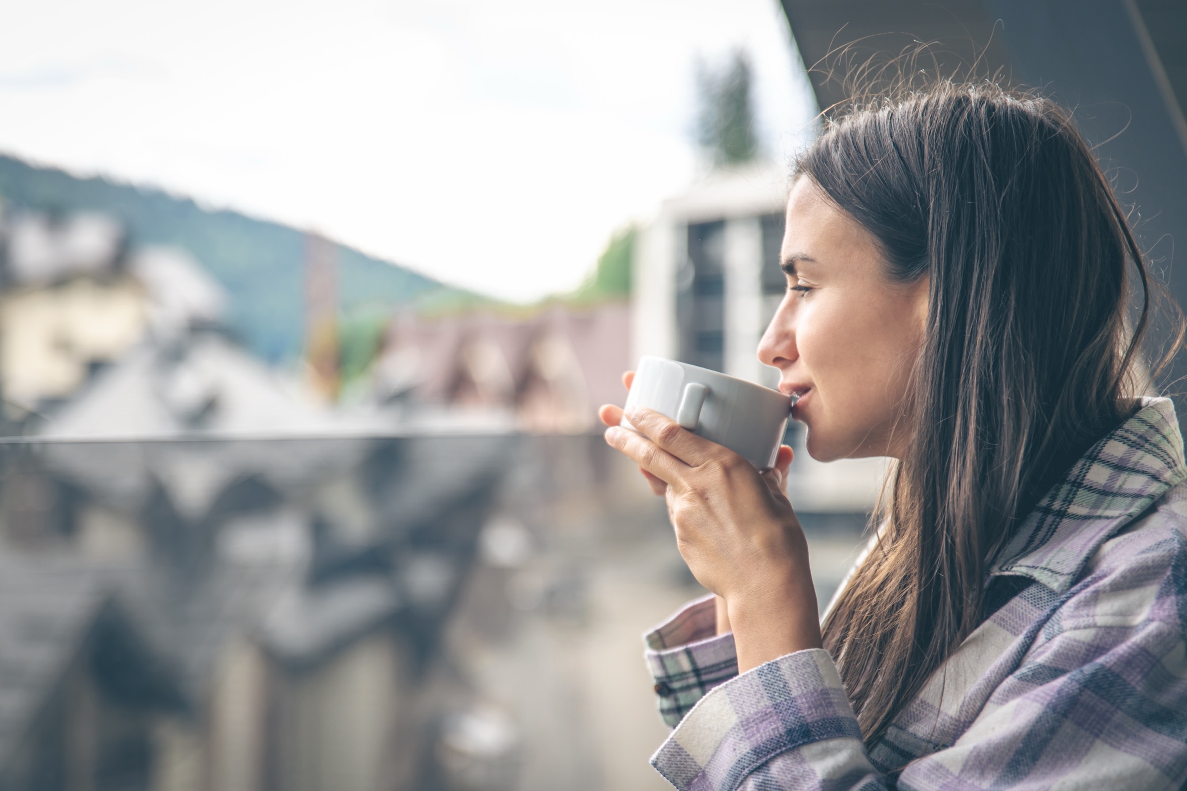 Frau trinkt am Morgen auf dem Balkon einen Kaffee